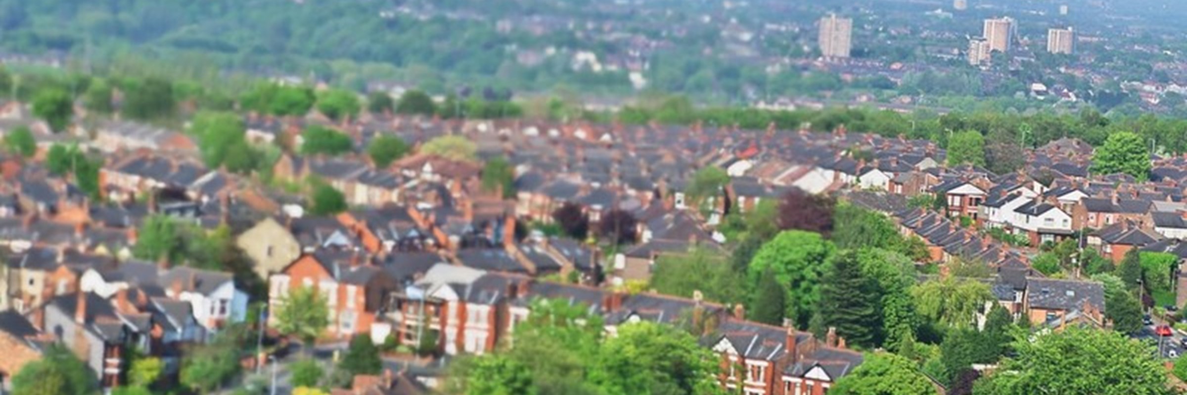 Birds eye view of homes and greenery in a residential area and Greater Manchester city centre in the distance