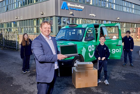 An image of a head teacher with pupils receiving a device donation