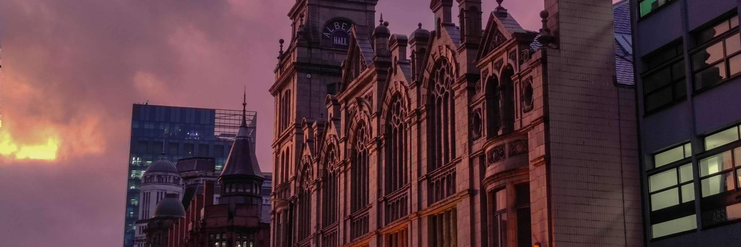 a city street at dusk with buildings and a clock tower