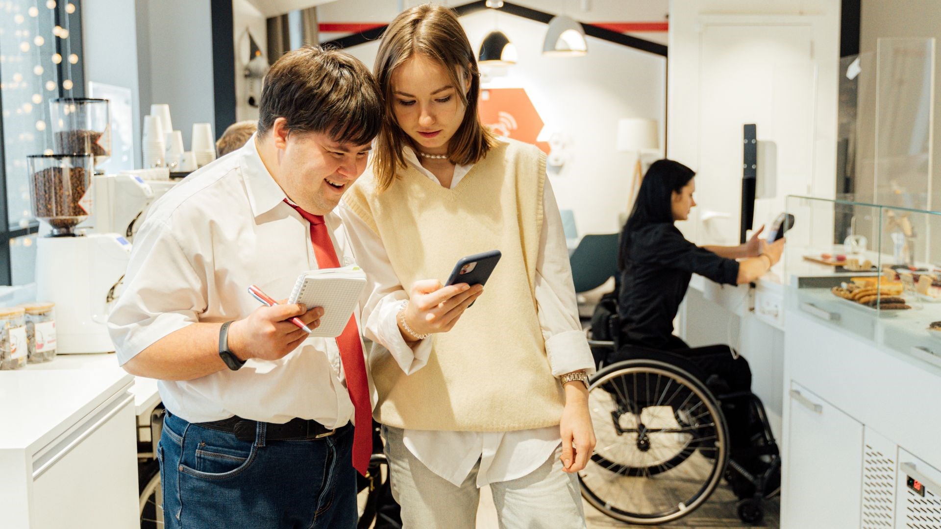 a person in a wheelchair and two people looking at a mobile phone