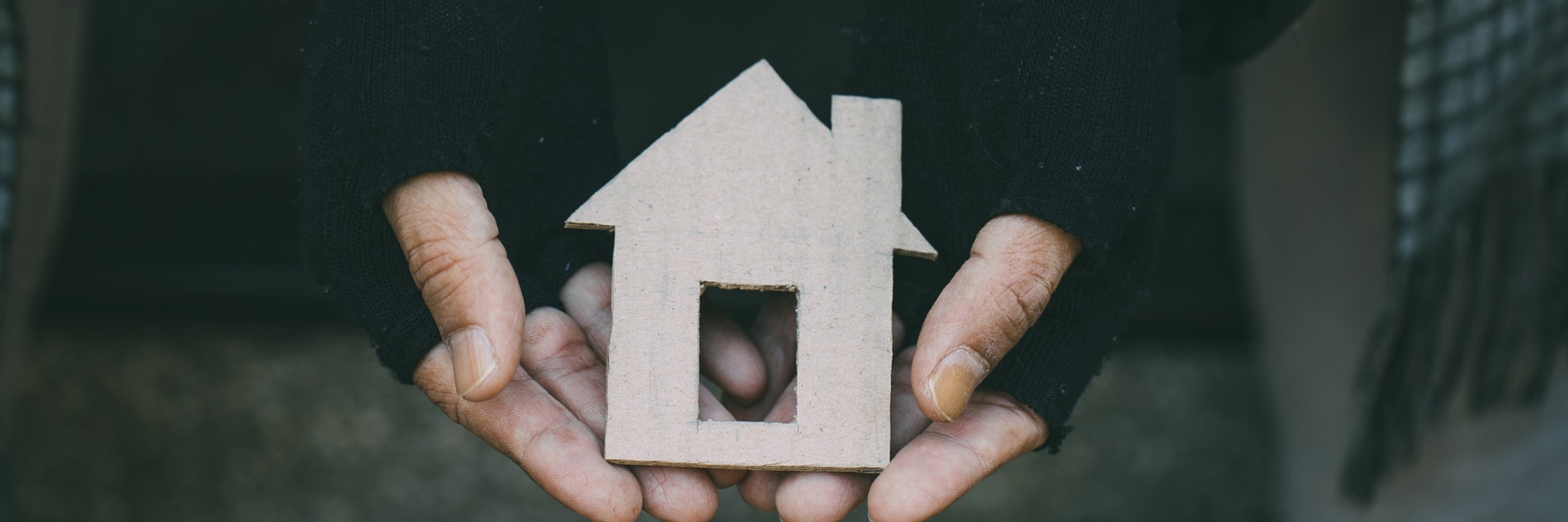 Man experiencing homelessness holding a cardboard house. nostalgia and hope concept.