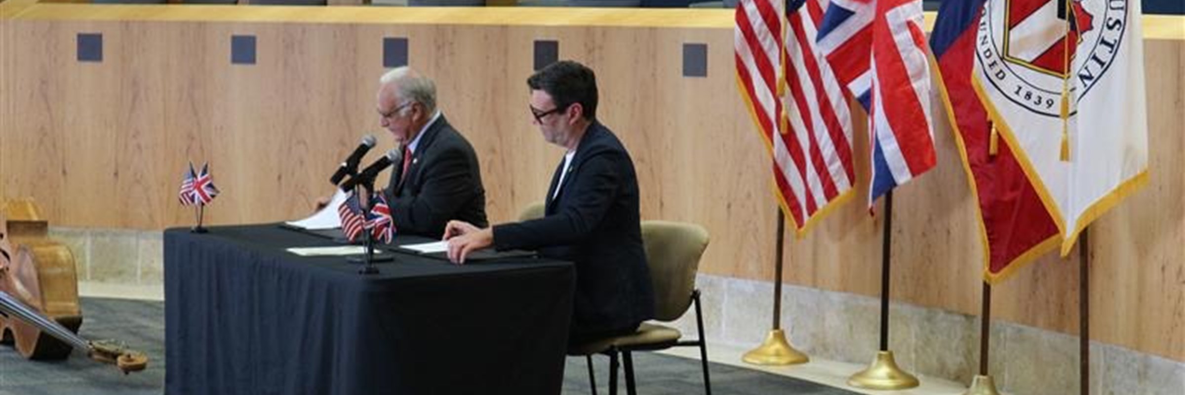 Andy at a table with another man, at South by South West, with flags in the background