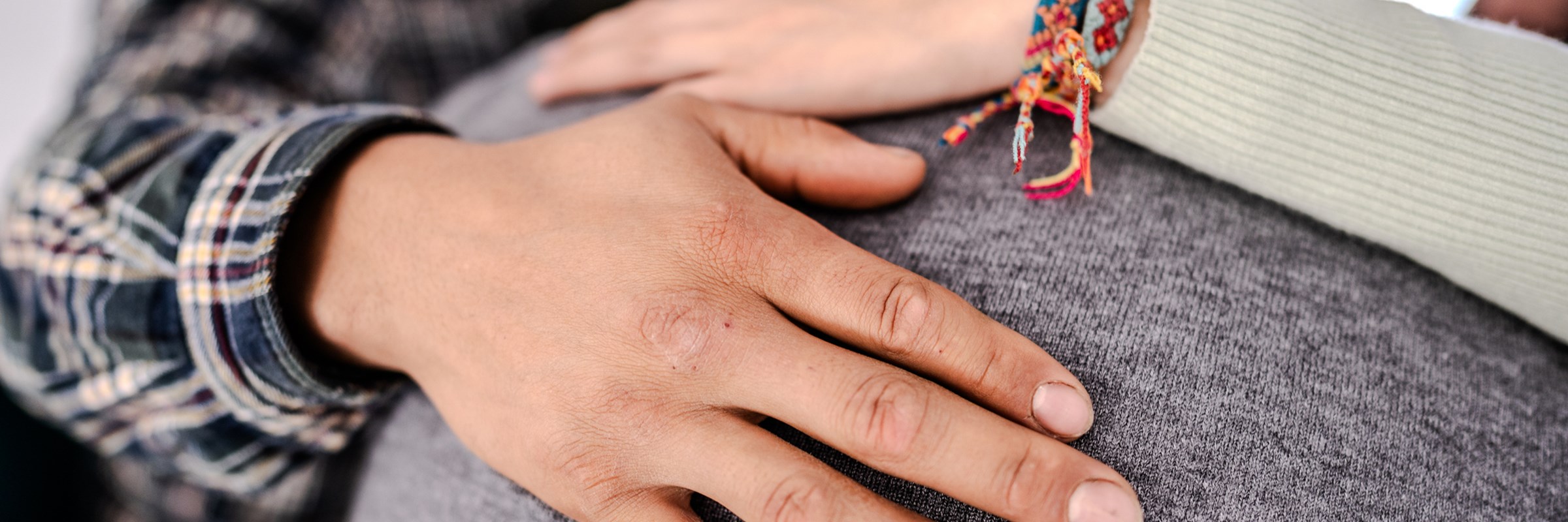 Close-up of a hand on the shoulder comforting another patient during a group therapy session