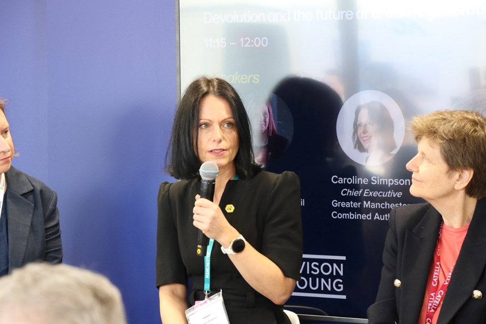 Caroline Simpson holds a microphone and speaks at a panel at MIPIM