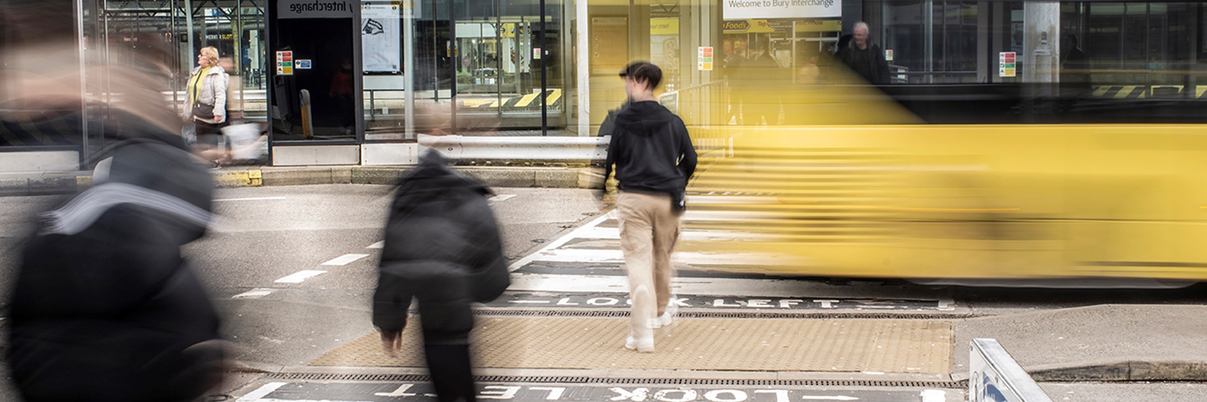 Bus driving past a zebra crossing in a Manchester city centre bus station