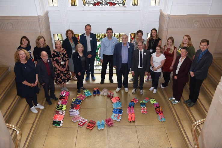 Andy Burnham with people in front of running shoes spelling out '10 m'