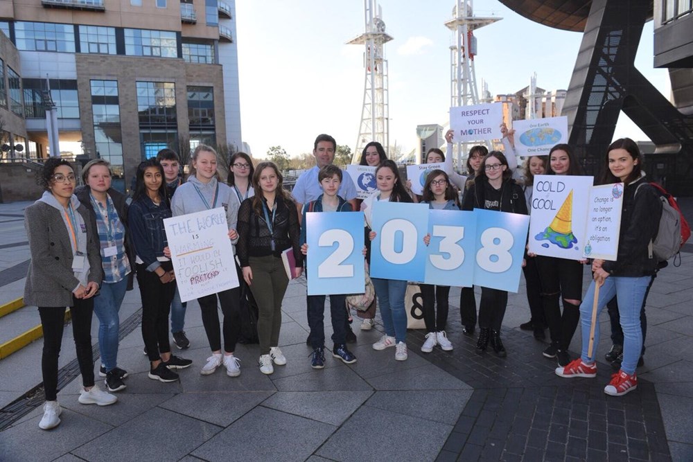 Andy Burnham with a group of people outside the Lowry holding banners about climate change