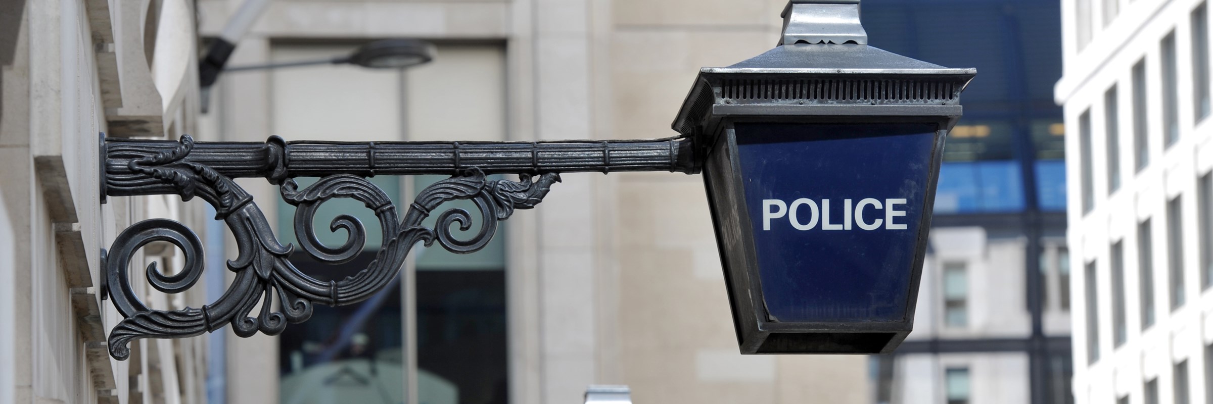 Traditional police blue lamp lantern signs hang above the entrance to a police office in central London