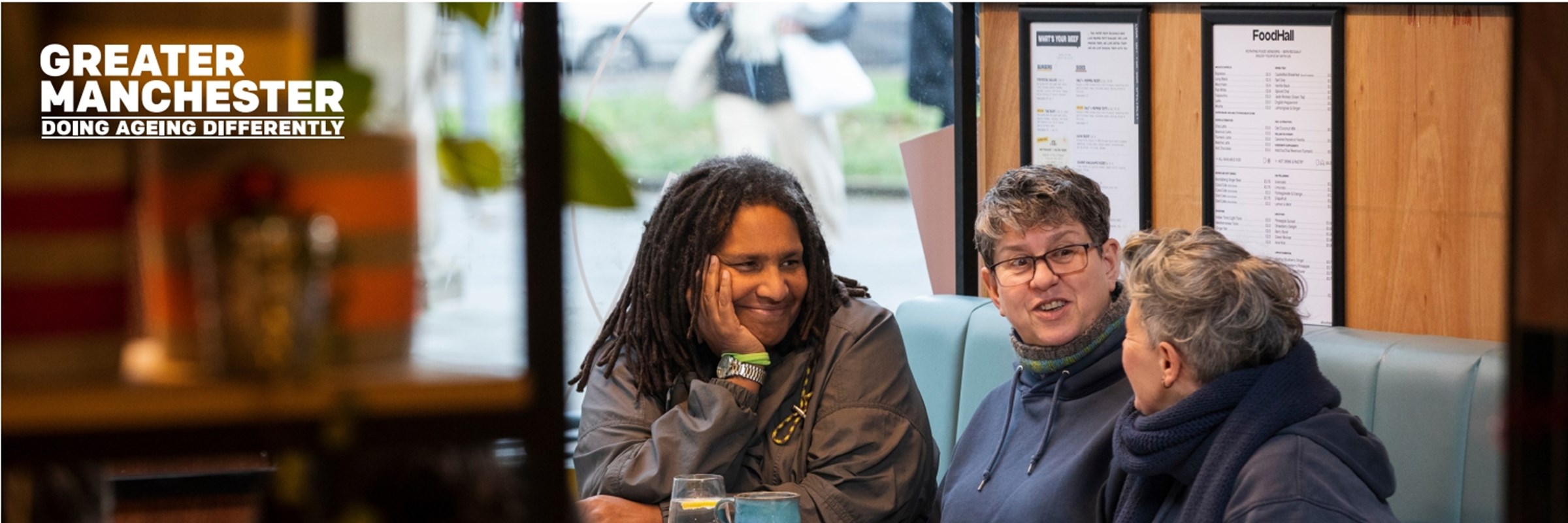 Three people sat talking in a booth at a cafe