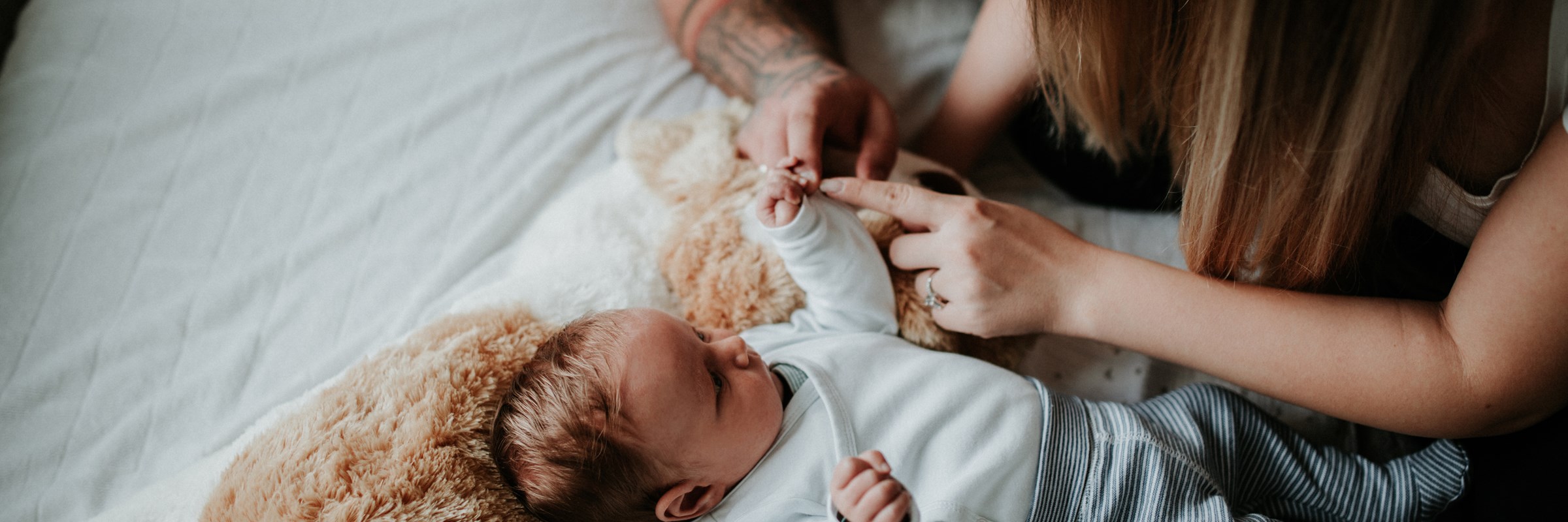 A man and a woman playing with a baby lying down on a soft toy