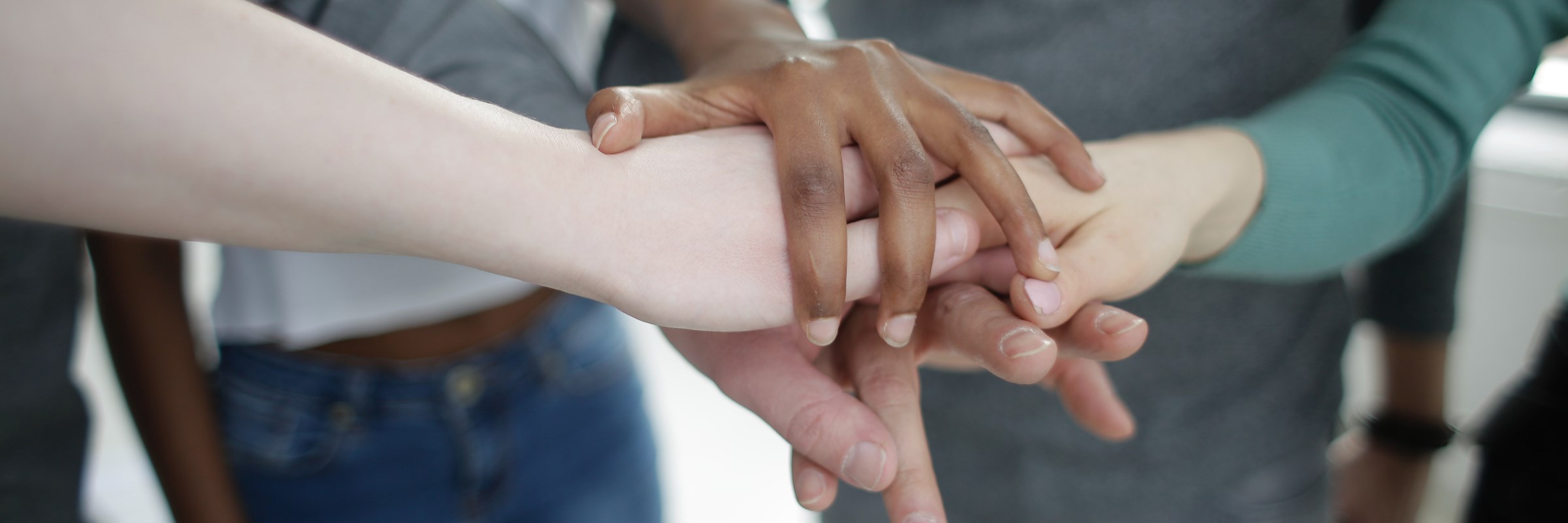 Five people have their hands on top of each other symbolising collaboration