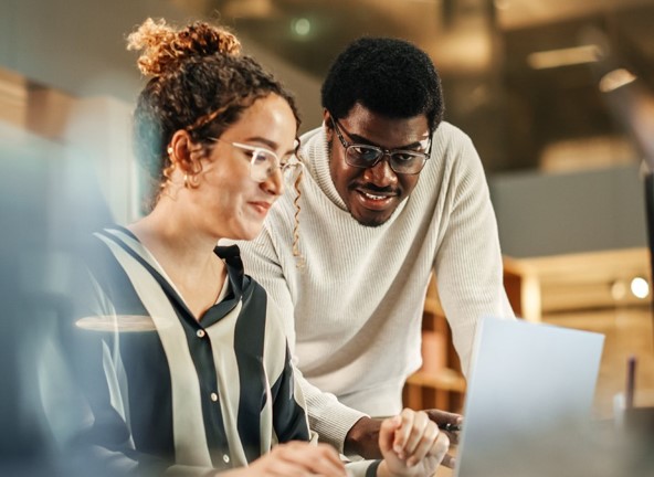 Two people both looking at a laptop screen