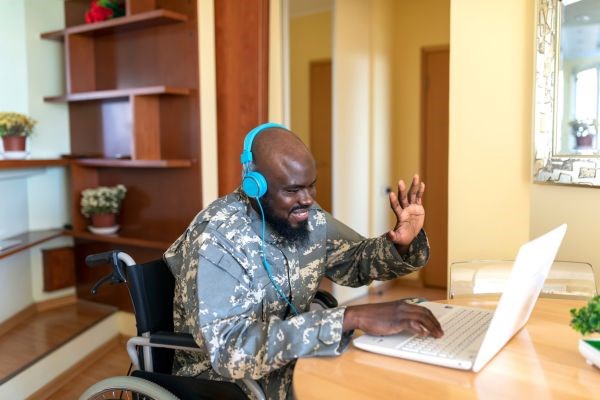 an individual in a wheelchair using a laptop with headphones on