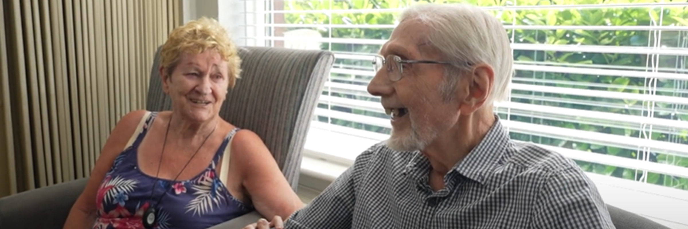 Two older people sat laughing with each other.