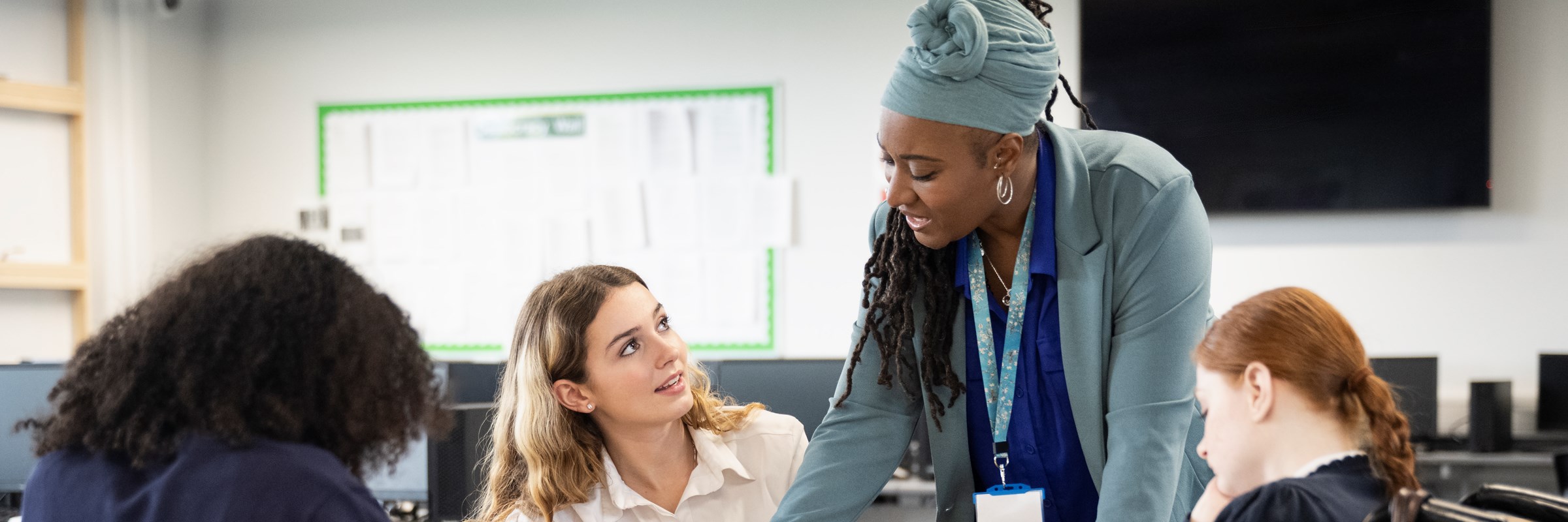 Female students working on assignment with help from teacher