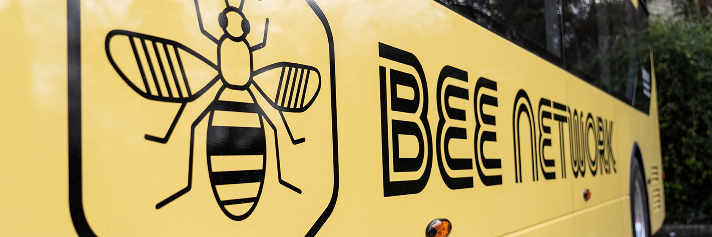 The bee network logo on the side of a double decker bus