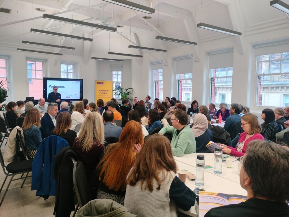 A group of people sitting at tables during an event, watching a presentation