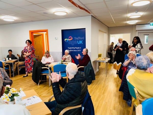 Older people sat down applauding at Age UK Trafford